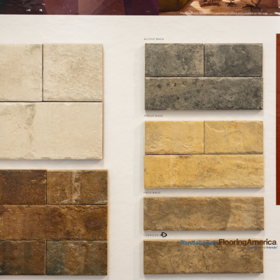 Showroom display of stone-look tiles in various colors and textures, featuring Alcove, Atrium, Patio, and Corridor collections.